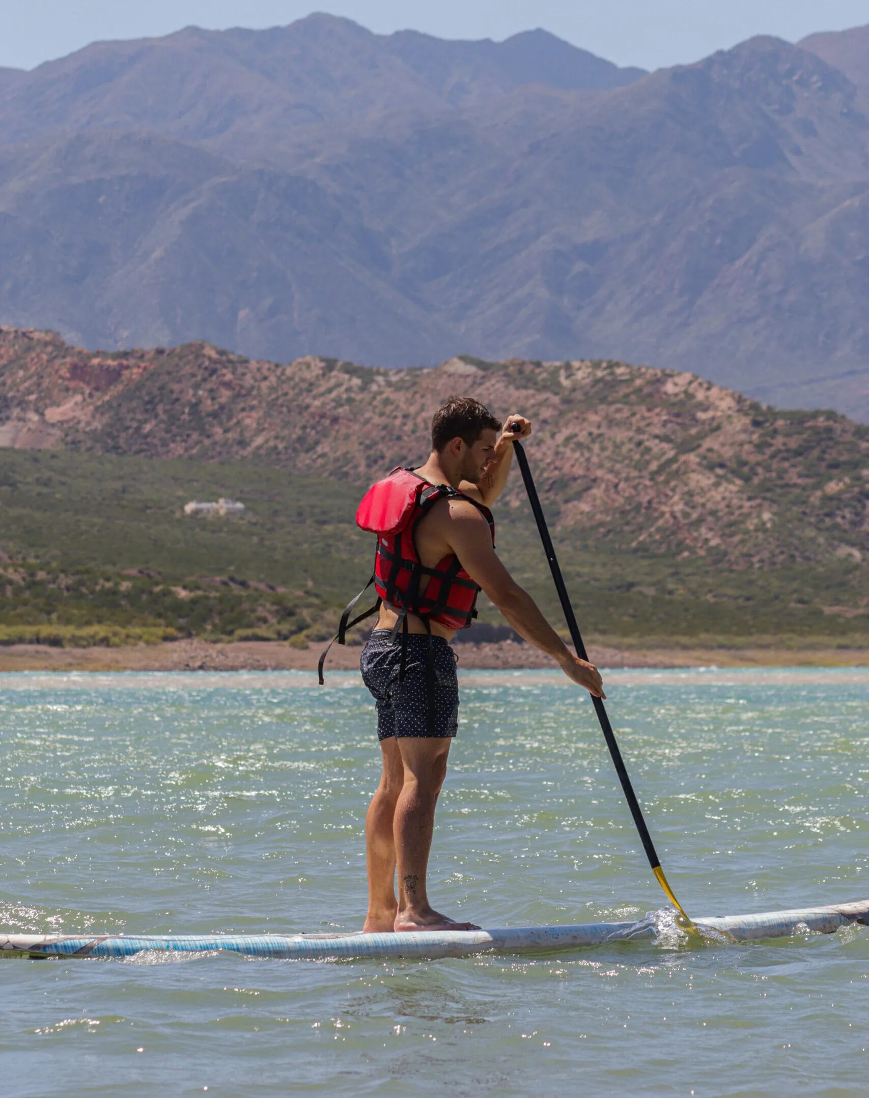 Persona haciendo Stand Up Paddle en un lago con montañas