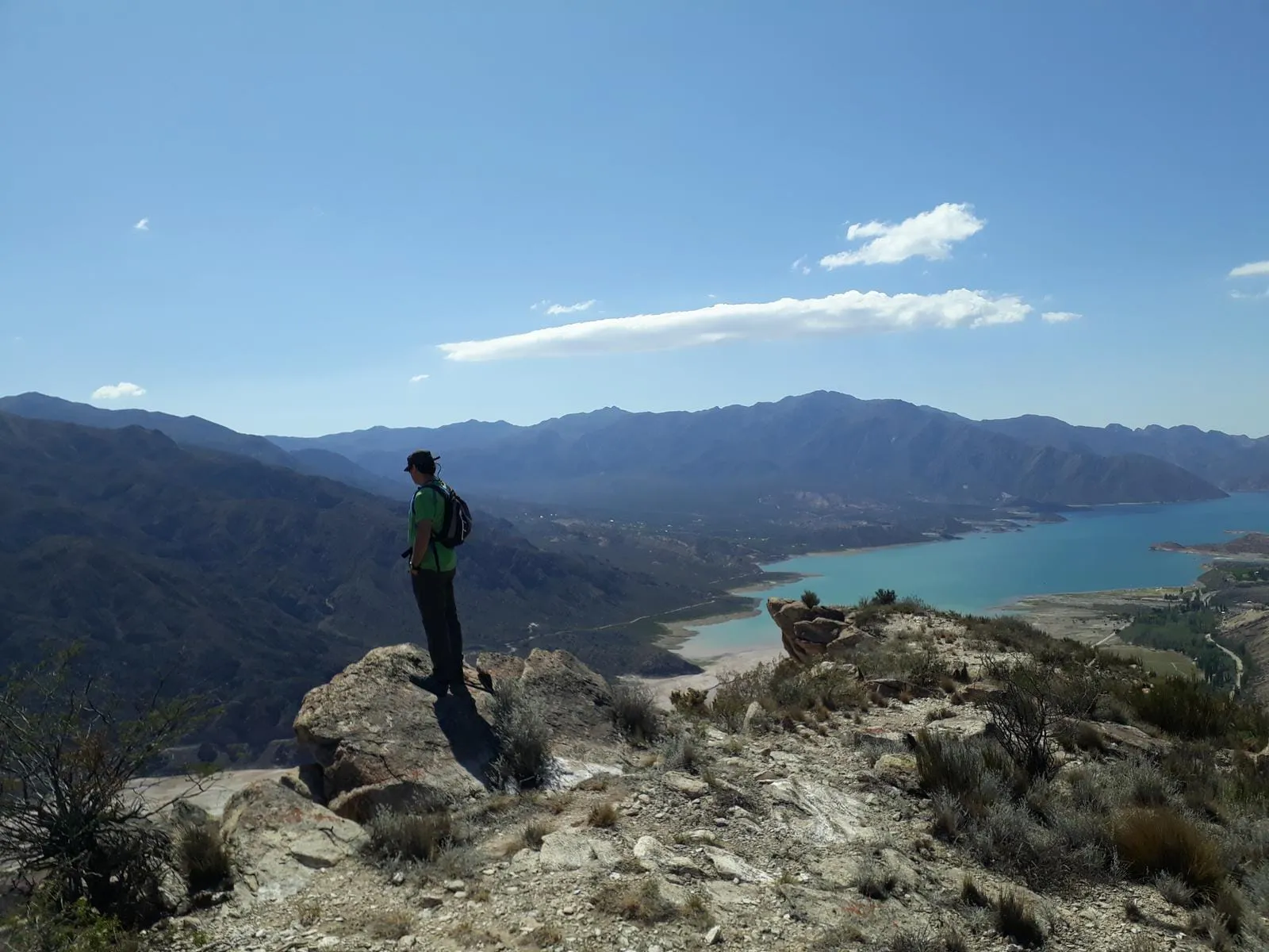 Persona haciendo trekking en un sendero de montaña con un valle de fondo